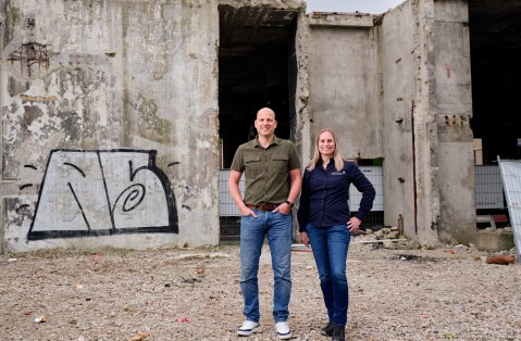 Hanneke Dekker, medewerker handhaving asbest (ODZOB), en Jordi de Ruijter, vergunningverlener asbest (ODZOB) op  een liggende foto naast elkaar bij een gebouw dat gesloopt wordt 