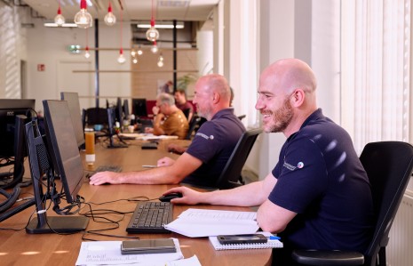 Collega bij ODZOB op kantoor aan het werk met op achtergrond meer collega's